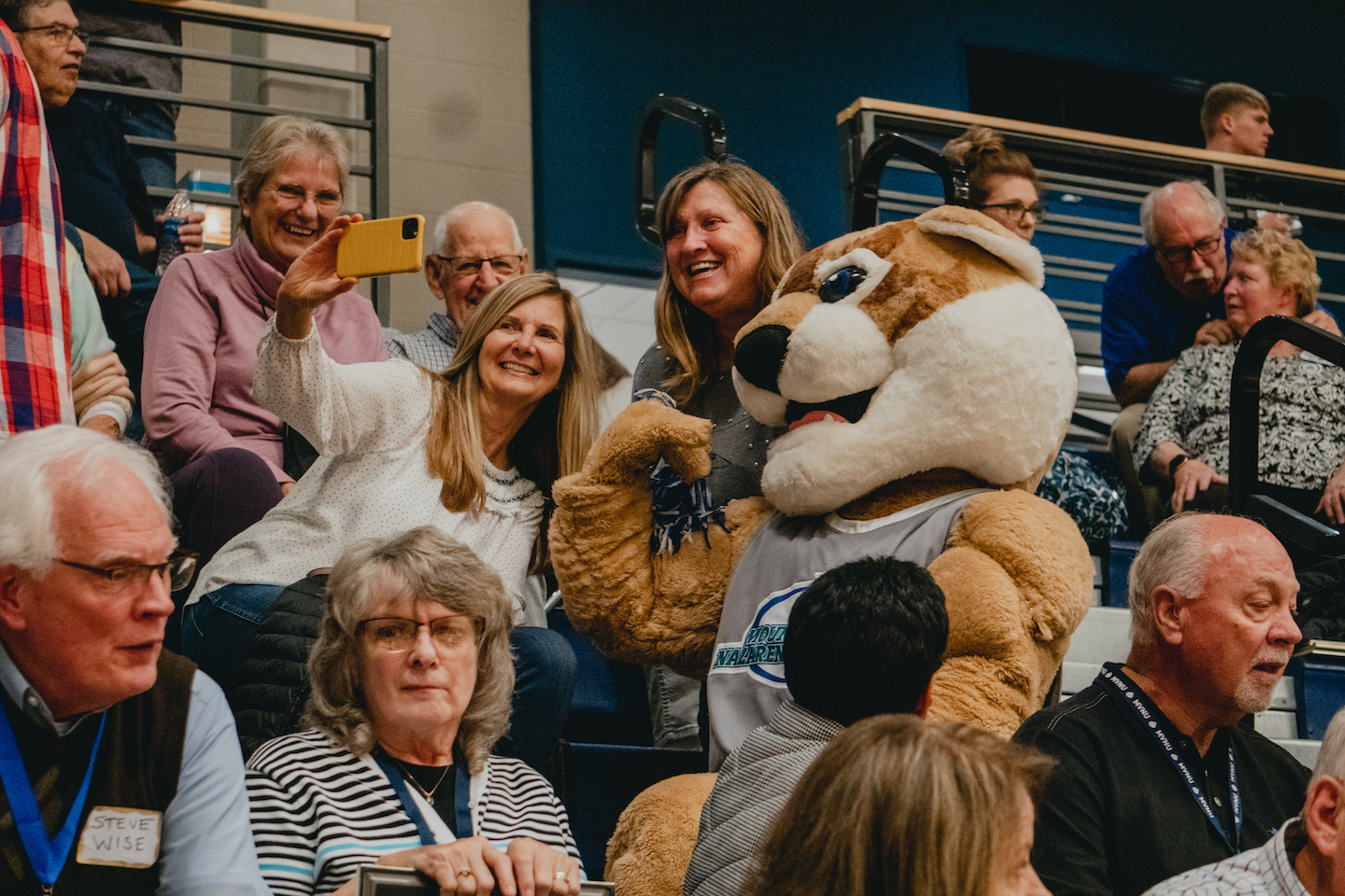 MVNU alumni pose with Casey Cougar during Homecoming basketball game.