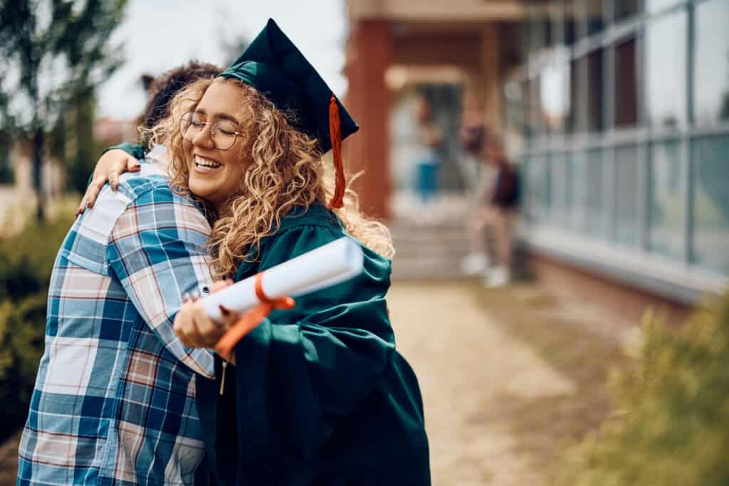 A college student embracing her father after her graduation ceremony.
