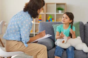 A social worker speaking with a young child and taking notes.
