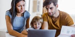 Woman and family juggling life’s responsibilities, such as reviewing bills, while pursuing an online education at MVNU, on a laptop at home