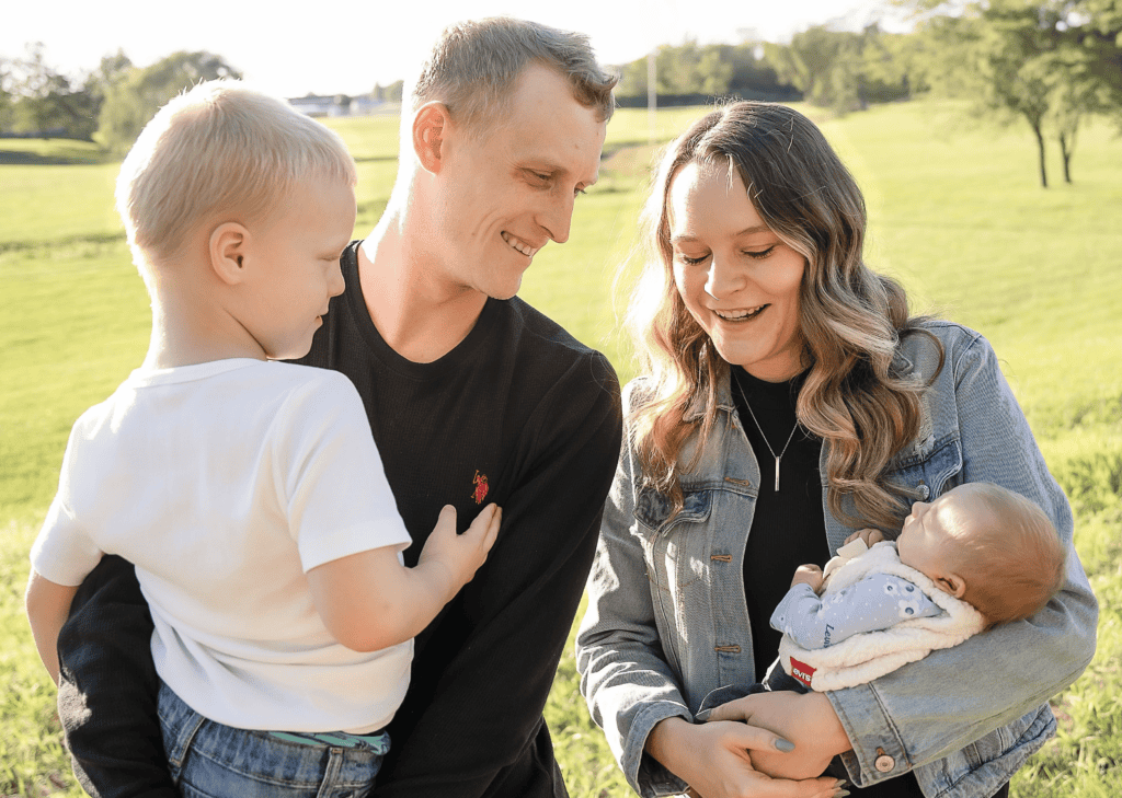 Ashley, an MVNU online elementary education student, smiling with her husband and two young children in a sunny outdoor setting.