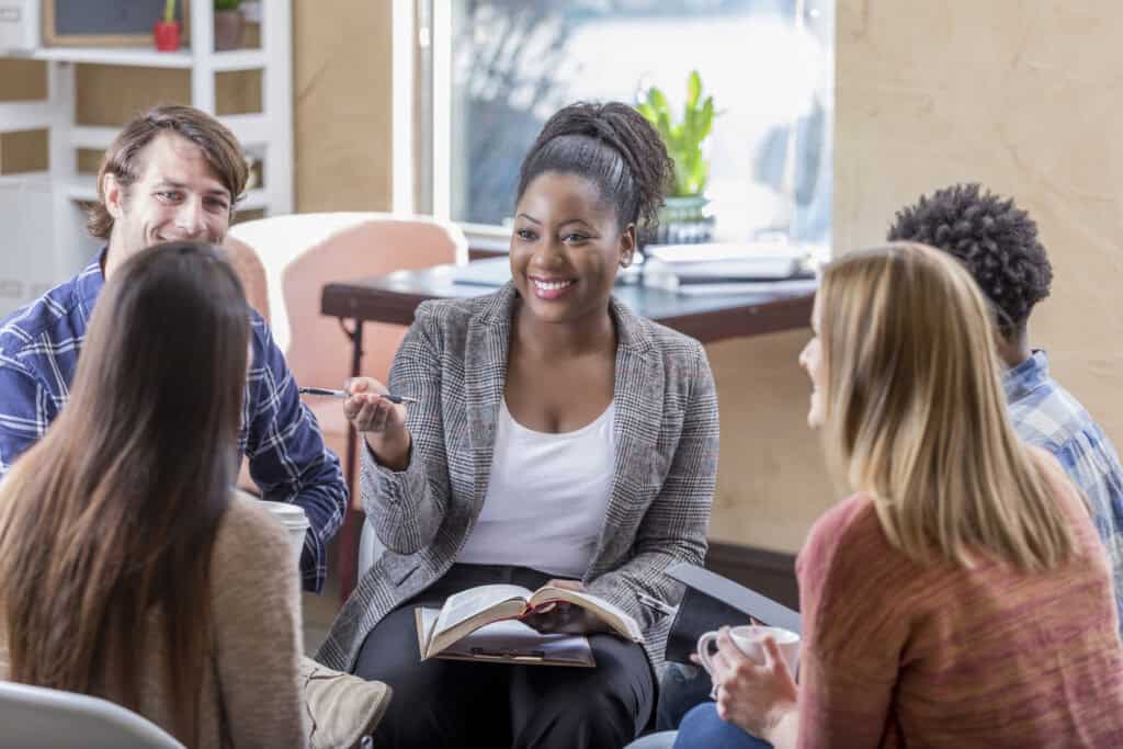 Adult students in a discussion group led by a woman with an open Bible, exploring how Christian values shape leadership, ethics, and service through MVNU’s online ministry degree programs.