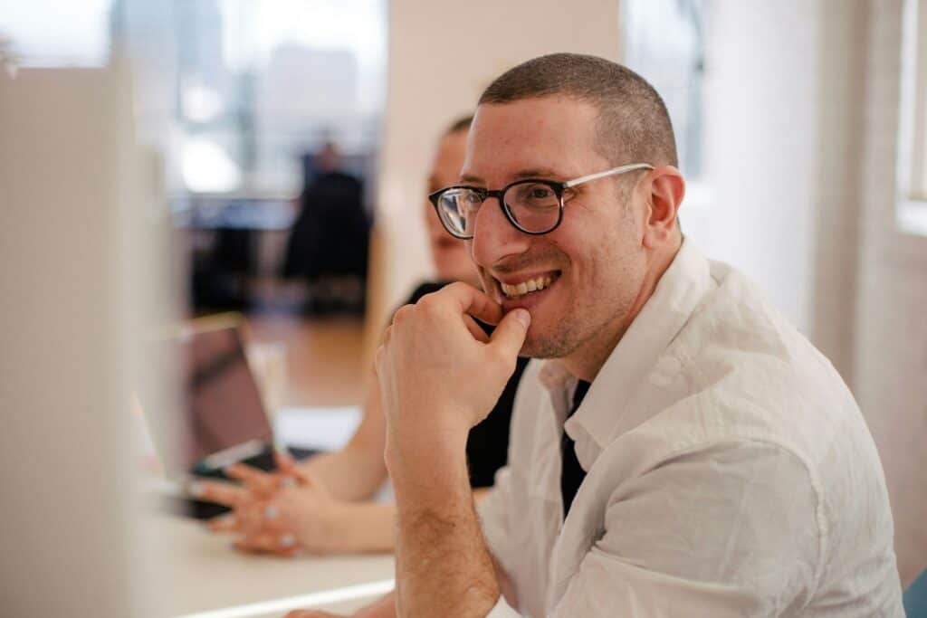 Smiling man in glasses engaged in conversation during an MSW Cincinnati online class setting