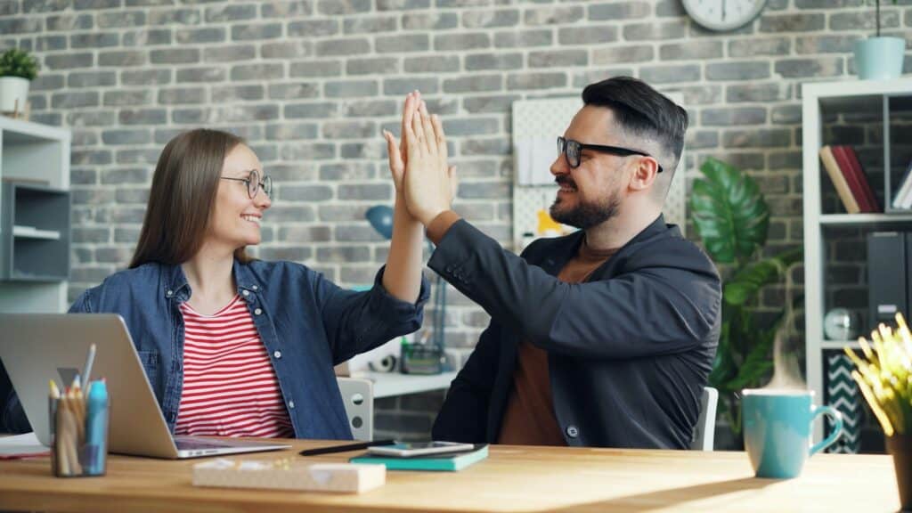 Two MSW Columbus students high-five while studying together online